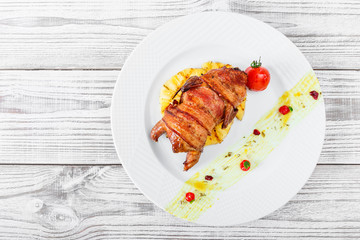 Grilled chicken in a ham with pineapple and tomatoes on plate on wooden background close up. Hot Meat Dishes. Top view