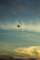 Fototapeta na wymiar Lecący samolot. Sylwetka samolotu na tle zachodzącego słońca. Kolorowe niebo.