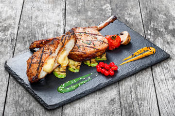 Roasted Pork steak on bone stuffed with cheese, grilled vegetables and berries on stone slate...