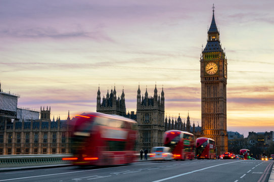 Big Ben with the Houses of Parliament and a red double-decker bus passing at dusk