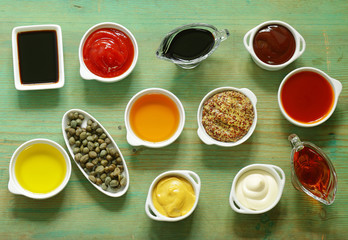 Different types of sauces and oils in bowls, top view
