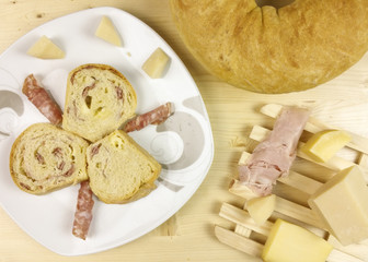 savory cake with salami, ham and cheese on wooden background - top view