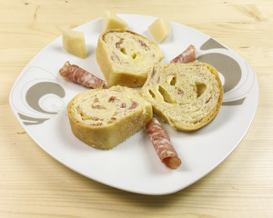 savory cake with salami, ham and cheese on wooden background - top view