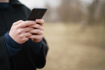 female young hands using smartphone outdoors in cold spring, copy space