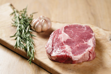 raw rib eye steak on board closeup, shallow focus