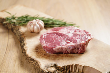 raw rib eye steak on board closeup, shallow focus