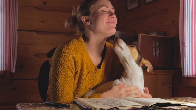 female artist cuddling with her dog while trying to also do some work at home studio, cozy cottage atmosphere