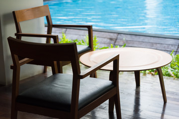 wooden chair and table place nearby the pool.