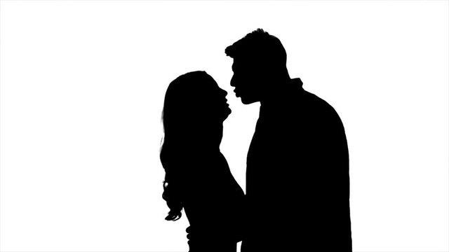 Lovers talk and try to kiss, flirt and start kissing each other. Silhouette. White background