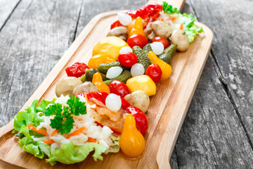 Assorted pickled vegetables - Sauerkraut cabbage, peppers, cucumbers, tomatoes, onions, mushrooms and herbs on cutting board