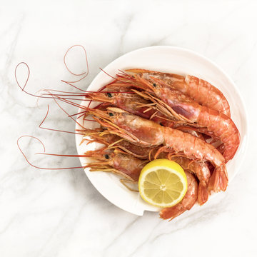 Raw shrimps with slice of lemon on plate