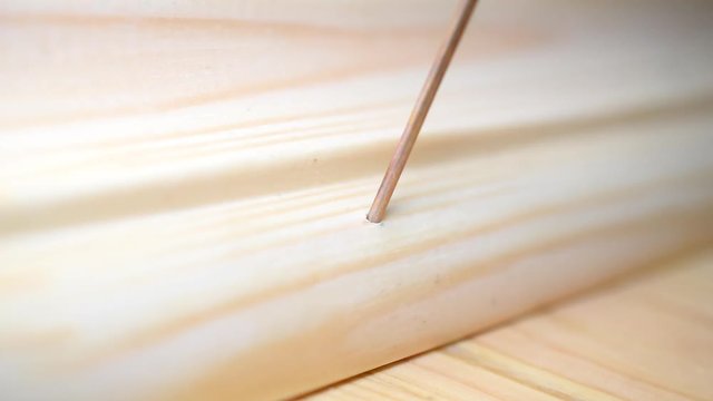 Male hands nailing a wooden skirting board with a hammer and nail in place