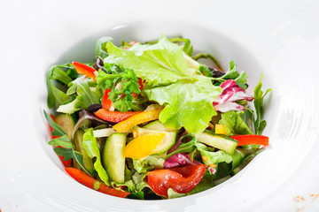 Fresh salad with cauliflower, arugula, lettuce, cherry tomatoes, cucumber, sweet pepper on wooden background. Top view