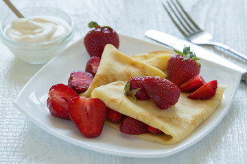 Pancakes with strawberries. On a white wooden background.
