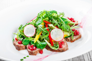 Salad with beef steak, baby spinach, lettuce, sweet pepper and grains of pomegranate on wooden background close up. Top view