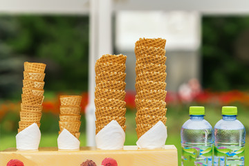 Many empty wafer sweet cornets for ice cream on naturale green blurry background. Selective focus. Copy space. Real scene in the store. Concept of summer, sweets