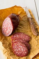 Cut beef salami  on white wooden table with cutting knife