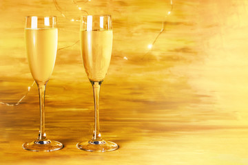 Two glasses of champagne on blurred golden background