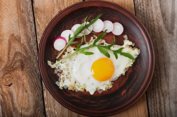 Toasted egg with onions, decorated with arugula and radish.