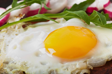 Toasted egg with onions, decorated with arugula and radish.