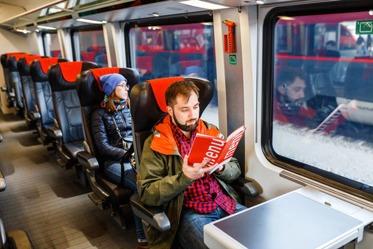 A handsome bearded man, travels in a train and reads a menu