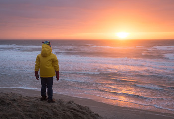 Child observing sunset on a winter beach in Texel,  the Netherlands.