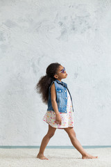 Cute afro girl against the gray wall
