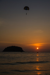 Peoples fly on a parachute under sea in the evening