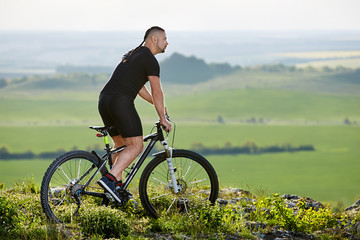 Fototapeta premium Cyclist standing with mountain bike on background of beautiful landscape.