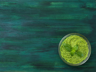 Homemade green pesto sauce and basil on a wooden board. 