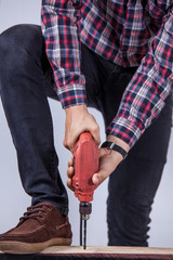Midsection of man drilling nail on table