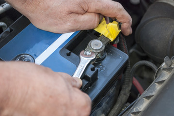 Kfz-Mechaniker tauscht eine defekte Autobatterie in einer Werkstatt aus