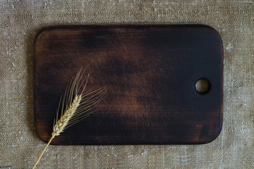 Wheat ear on a kitchen board on a sacking background