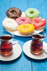 Two cups of tea and donuts on a blue wooden table