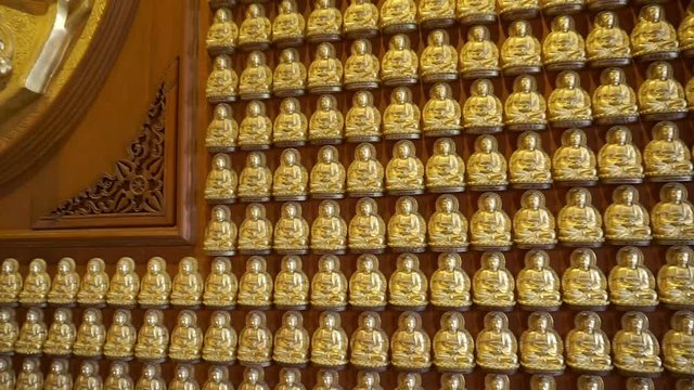 Golden buddha at wall in temple (Panning shot)