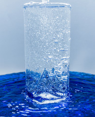 A glass of water, water with bubbles overflows through glass