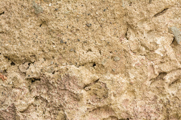 Texture of the old concrete wall with a damaged surface and small cracks, on some parts of the wall moss grows
