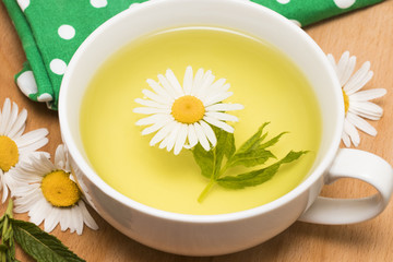cup of herbal tea with chamomile flowers on a wooden table