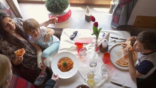 Happy family in restaurant in vacation in mountains with kids eating pizza high shot