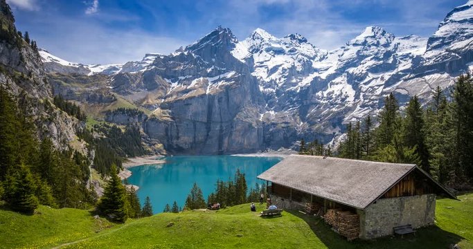 Amazing tourquise Oeschinnensee lake with waterfalls, wooden chalet and Swiss Alps, Berner Oberland, Switzerland. 
