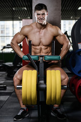 Naklejka premium Muscular handsome athletic bodybuilder fitness model posing after exercises in gym on diet .