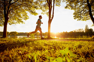 Young man running in park during sunset