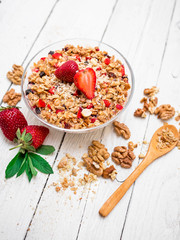 Oatmeal porridge with strawberries and muesli on white wooden table. Flat lay. Top view.