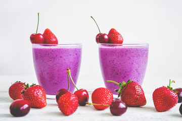 Blueberry and strawberry smoothie and tasty summer berries on white wooden table. Fresh natural milkshake