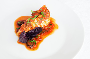 chicken cooked in tomato sauce decorated with parsley and basil