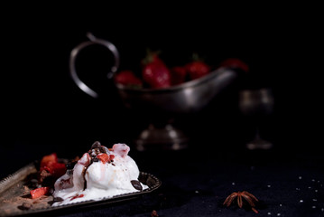 White icecream with chocolate and strawberry on the black background