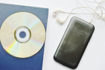 book and CD- rom with earphones connect in smartphone on white background