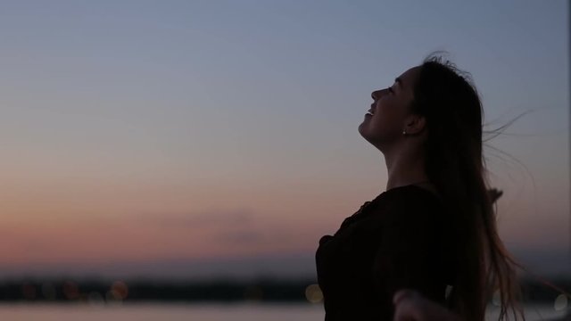 Silhouette of woman enjoying freedom on a bridge in evening