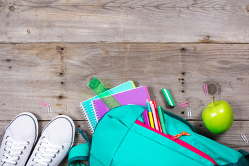 Backpack with school stationery on wooden background