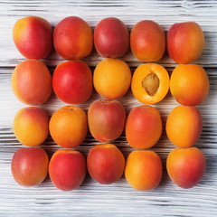 Top view of ripe apricots on white wooden background